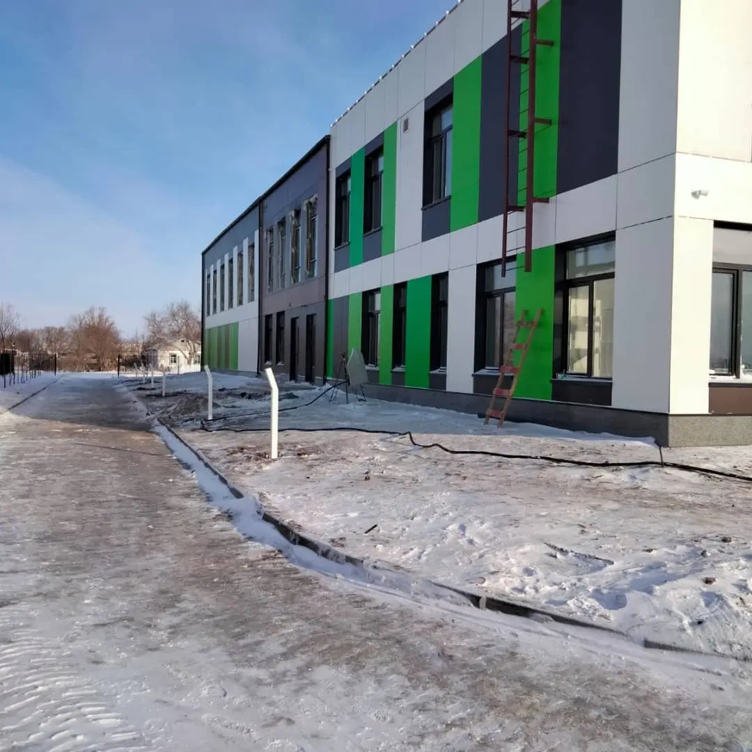 Готовое двухэтажное здание с бело-серым фасадом и зелёными вставками